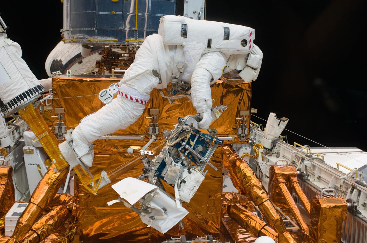 S125-E-007563 (15 May 2009) --- Astronaut Michael Good works with the Hubble Space Telescope in the cargo bay of the Earth-orbiting Space Shuttle Atlantis. Astronauts Good and Mike Massimino (working background) participated in the second session of STS-125 extravehicular activity -- as part of a five-day beehive-like agenda of spacewalking and work on the giant orbital observatory.