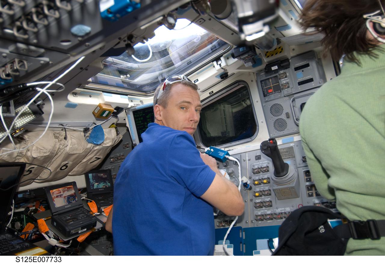 S125-E-007733 (15 May 2009) --- Astronauts Andrew Feustel and Megan McArthur (partially visible at right), STS-125 mission specialists, concentrate on various chores in support of the Atlantis' second session of extravehicular activity. They are positioned on the aft side of the crew cabin, where controls for the remote manipulator system arm, among other important elements, are located. Feustel?s tandem, which also includes astronaut John Grunsfeld (out of frame), is assigned interior duty for this session but tomorrow will once again don extravehicular mobility units and go outside Atlantis for its second of three assigned spacewalks.