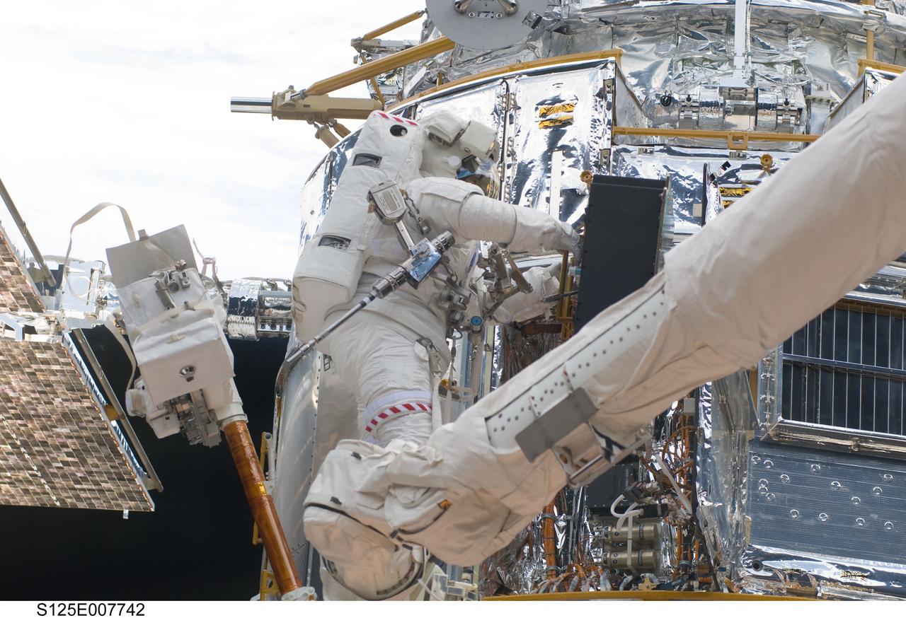 S125-E-007742 (15 May 2009) --- While standing on the end of Atlantis' remote manipulator system arm, astronaut Michael Good, STS-125 mission specialist, works on the Hubble Space Telescope.  Astronauts Good and Mike Massimino (out of frame), mission specialist, continue work on the Hubble Space Telescope, locked down in the orbiter's cargo bay. After their May 15 tasks were completed, three more sessions of extravehicular activity, on back to back to back days, awaited the seven-person crew.