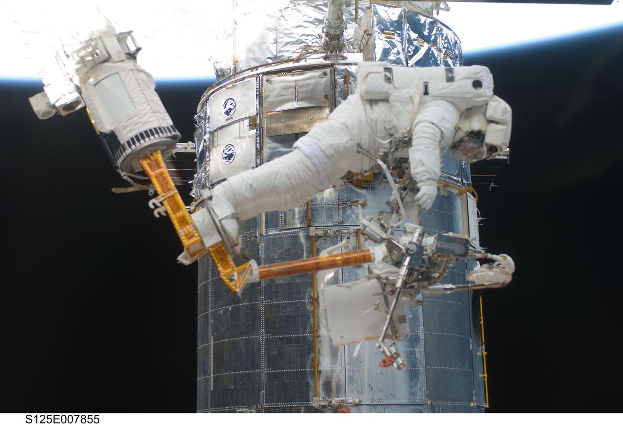 S125-E-007855 (16 May 2009) ---   Astronaut Andrew Feustel, STS-125 mission specialist,  reaches for a power tool as he navigates near the Hubble Space Telescope on the end of the remote manipulator system arm, controlled from inside Atlantis? crew cabin. Astronauts Feustel and John Grunsfeld were continuing servicing work on the giant observatory, locked down in the cargo bay of the  shuttle.