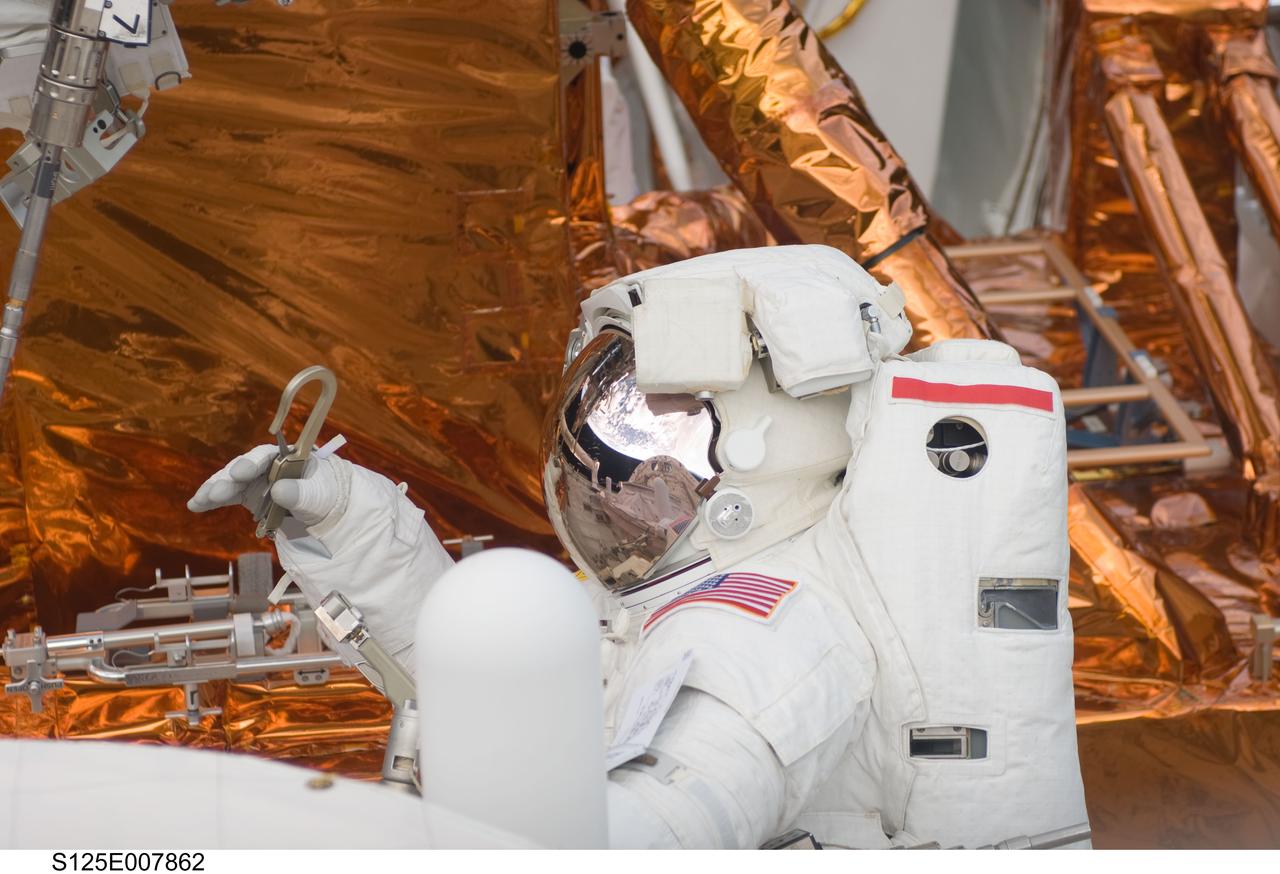 S125-E-007862 (16 May 2009) --- Astronaut John Grunsfeld, STS-125 mission specialist,  is about to attach a tether during a May 16 spacewalk to perform work on the Hubble Space Telescope.