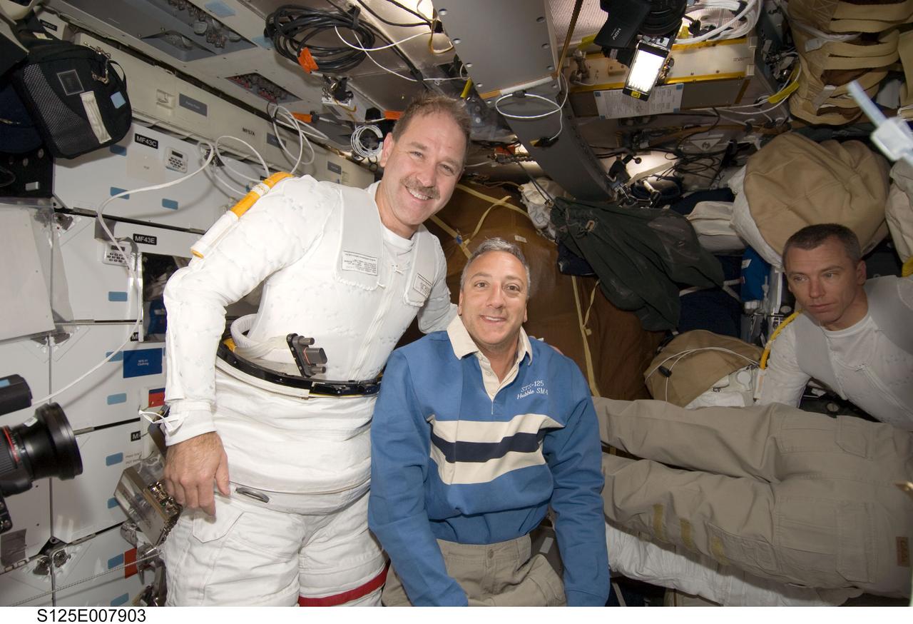 S125-E-007903 (16 May 2009) --- Astronaut John Grunsfeld (left) and Mike Massimino, both STS-125 mission specialists, take a moment for a photo on the middeck of Space Shuttle Atlantis, as they prepare for the mission?s third session of extravehicular activity (EVA). Astronaut Andrew Feustel, mission specialist, is at right.