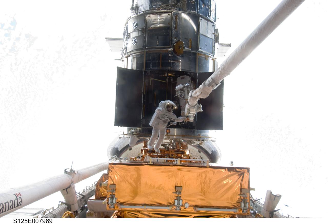 S125-E-007969 (16 May 2009) --- Astronauts Andrew Feustel (left) and John Grunsfeld, both STS-125 mission specialists, participate in the mission?s third session of extravehicular activity (EVA) as work continues to refurbish and upgrade the Hubble Space Telescope. During the six-hour, 36-minute spacewalk, Grunsfeld and Feustel removed the Corrective Optics Space Telescope Axial Replacement and installed in its place the new Cosmic Origins Spectrograph. They also completed the Advanced Camera for Surveys electronic card replacement work, and completed part 2 of the ACS repair, installing a new electronics box and cable.