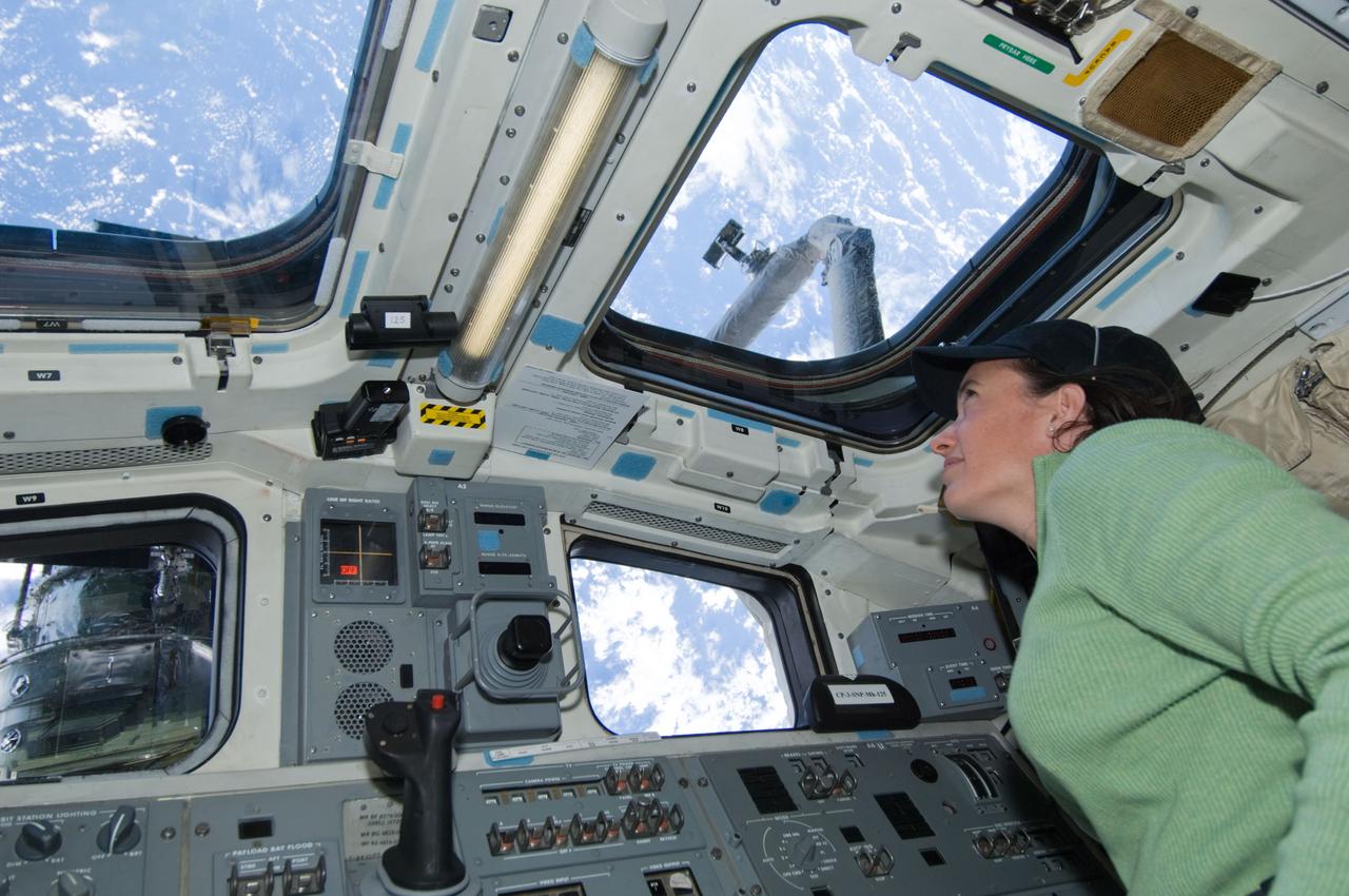 S125-E-007993 (16 May 2009) --- Astronaut Megan McArthur, STS-125 mission specialist, looks through an overhead window on the aft flight deck of Space Shuttle Atlantis during flight day six activities.