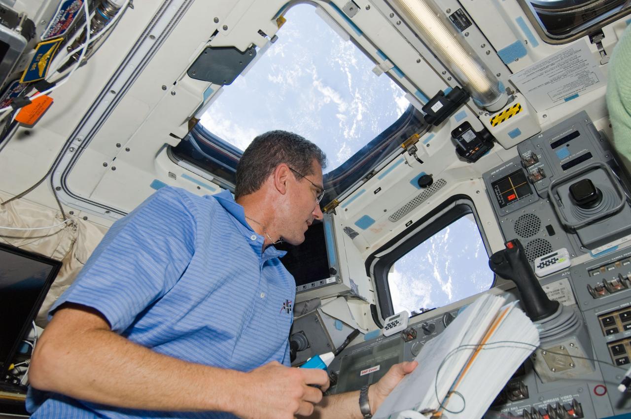 S125-E-007995 (16 May 2009) --- Astronaut Michael Good, STS-125 mission specialist, looks through an overhead window on the aft flight deck of Space Shuttle Atlantis during flight day six activities.