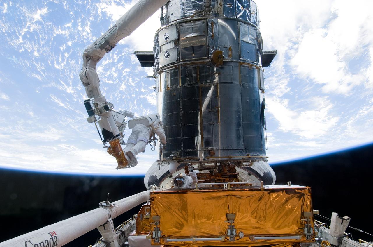S125-E-008007 (16 May 2009) --- Astronauts Andrew Feustel and John Grunsfeld (partially obscured at bottom), both STS-125 mission specialists, participate in the mission?s third session of extravehicular activity (EVA) as work continues to refurbish and upgrade the Hubble Space Telescope. During the six-hour, 36-minute spacewalk, Grunsfeld and Feustel removed the Corrective Optics Space Telescope Axial Replacement and installed in its place the new Cosmic Origins Spectrograph. They also completed the Advanced Camera for Surveys electronic card replacement work, and completed part 2 of the ACS repair, installing a new electronics box and cable.