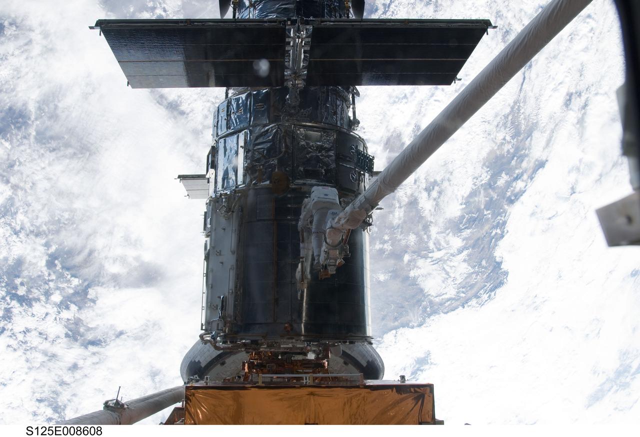 S125-E-008608 (17 May 2009) --- Astronaut Michael Good, STS-125 mission specialist, rides Atlantis' remote manipulator system arm to the exact position he needs to be to continue work on the Hubble Space Telescope.  Astronaut Mike Massimino, who shared two spacewalks with Good during the last week, is out of frame.