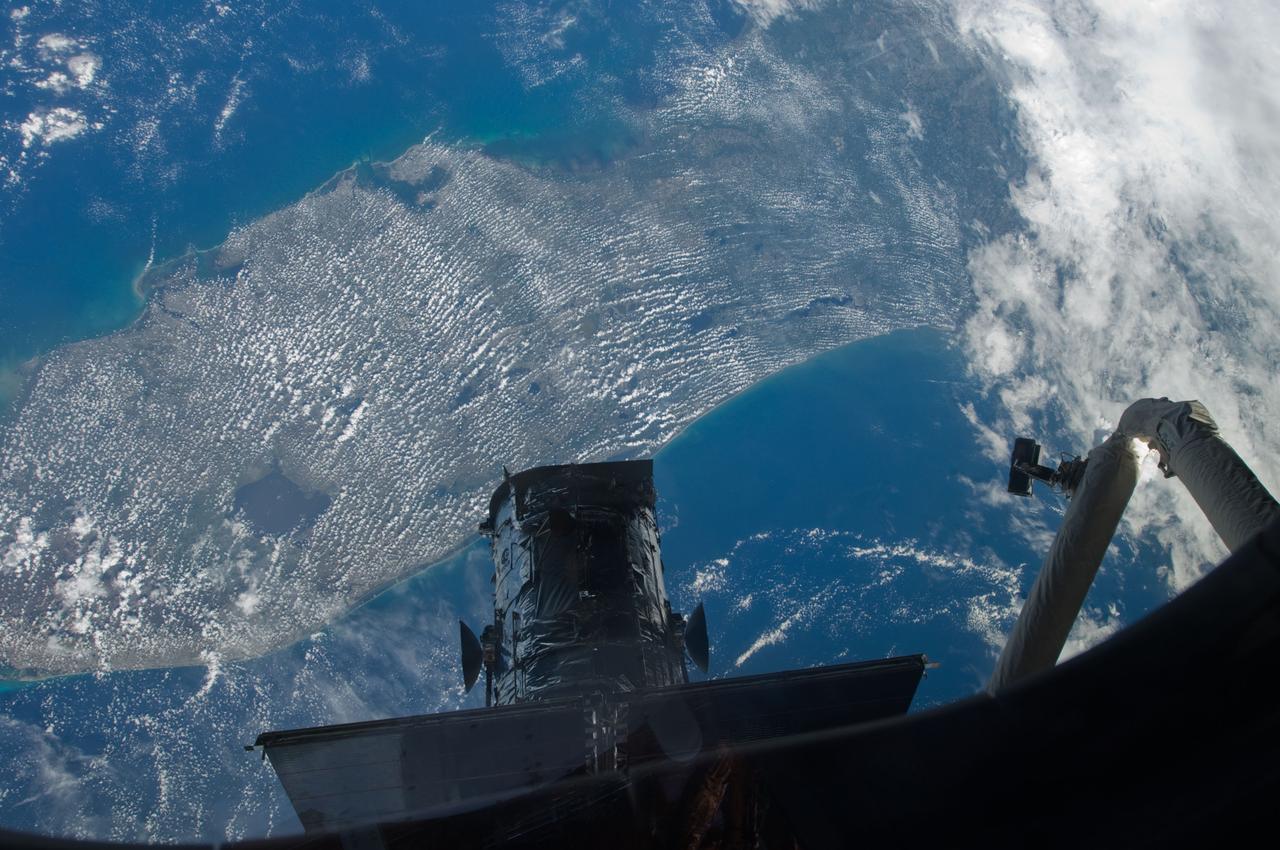 S125-E-008618 (17 May 2009) --- Part of the giant Hubble Space Telescope is silhouetted over the Florida peninsula in this photo recorded by one of the crewmembers aboard the Space Shuttle Atlantis. At the conclusion of today's extravehicular activity, the orbital observatory awaited one final day of STS-125 spacewalks to complete work on it for the last time.
