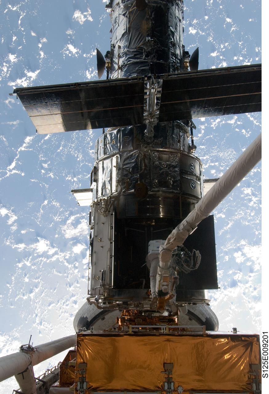 S125-E-009201 (17 May 2009) --- Astronaut Michael Good, STS-125 mission specialist, rides Atlantis' remote manipulator system arm to the exact position he needs to be to continue work on the Hubble Space Telescope.  Astronaut Mike Massimino, who shared two spacewalks with Good during the last week, is out of frame.