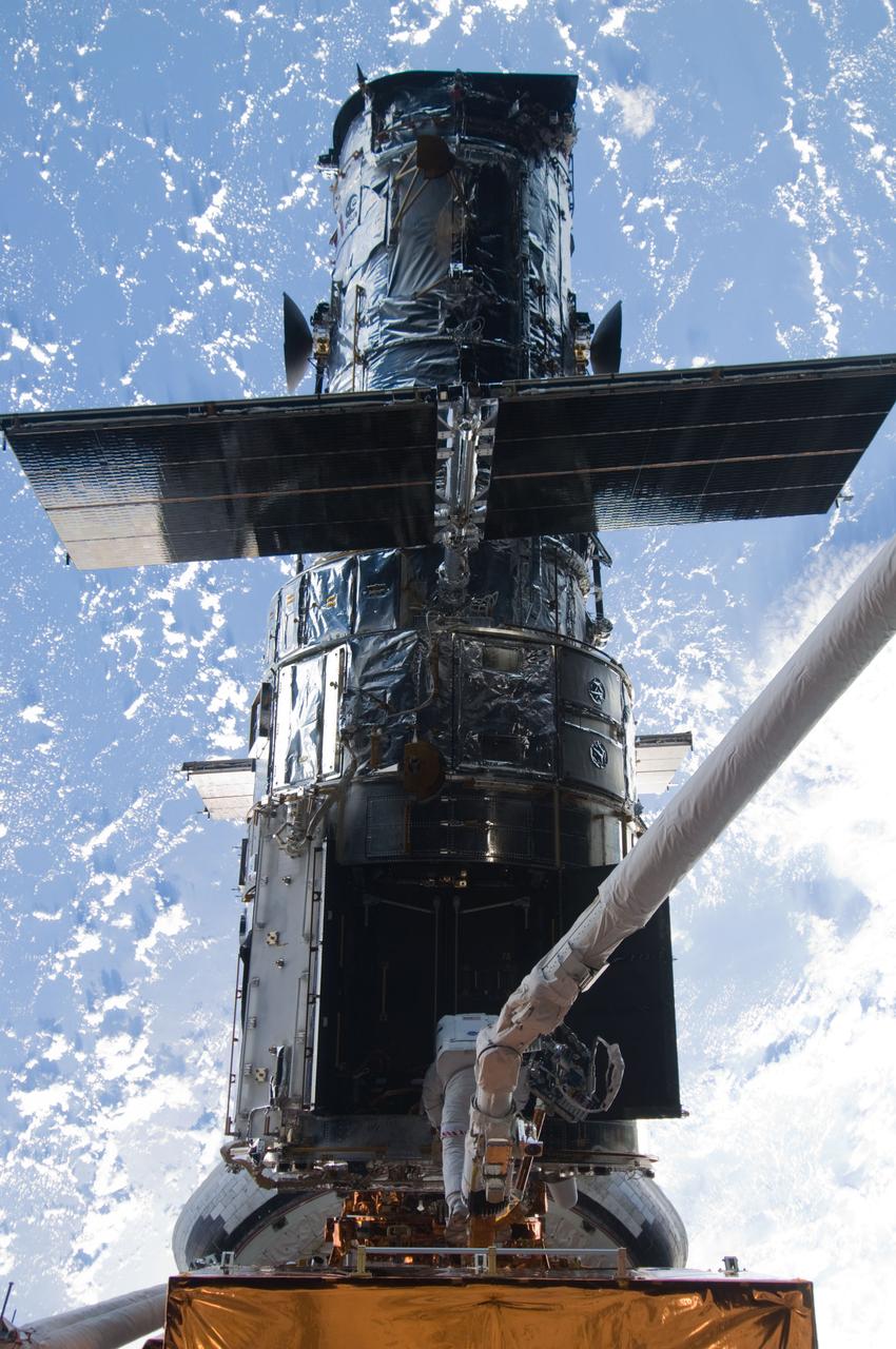 S125-E-009213  (17 May 2009) --- Astronaut Michael Good, STS-125 mission specialist, rides Atlantis' remote manipulator system arm to the exact position he needs to be to continue work on the Hubble Space Telescope.  Astronaut Mike Massimino, who shared two spacewalks with Good during the last week, is out of frame.