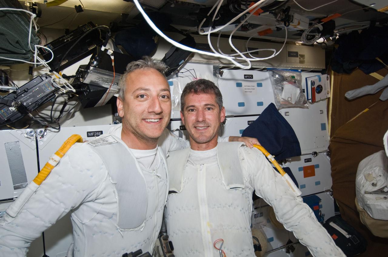 S125-E-009260 (17 May 2009) --- Astronauts Mike Massimino (left) and Michael Good, both STS-125 mission specialists, wearing the liquid cooling and ventilation garments that complement their Extravehicular Mobility Unit (EMU) spacesuits, pose for a photo on the middeck of Space Shuttle Atlantis following the completion of the mission?s fourth session of extravehicular activity (EVA).