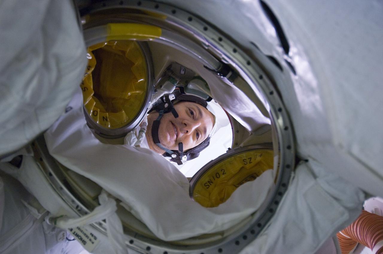 S125-E-009376 (17 May 2009) --- Astronaut Mike Massimino, STS-125 mission specialist, peers through an opening of his Extravehicular Mobility Unit (EMU) spacesuit on the Earth-orbiting Space Shuttle Atlantis prior to donning it in preparation for the mission?s fourth session of extravehicular activity.
