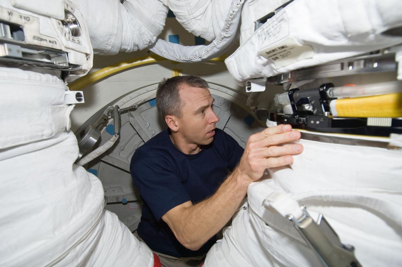 S125-E-009418 (17 May 2009) --- Astronaut Andrew Feustel, STS-125 mission specialist, assists astronauts Michael Good and Mike Massimino (both mostly out of frame), mission specialists, in the donning of their Extravehicular Mobility Unit (EMU) spacesuits on the Earth-orbiting Space Shuttle Atlantis in preparation for the mission?s fourth session of extravehicular activity (EVA).