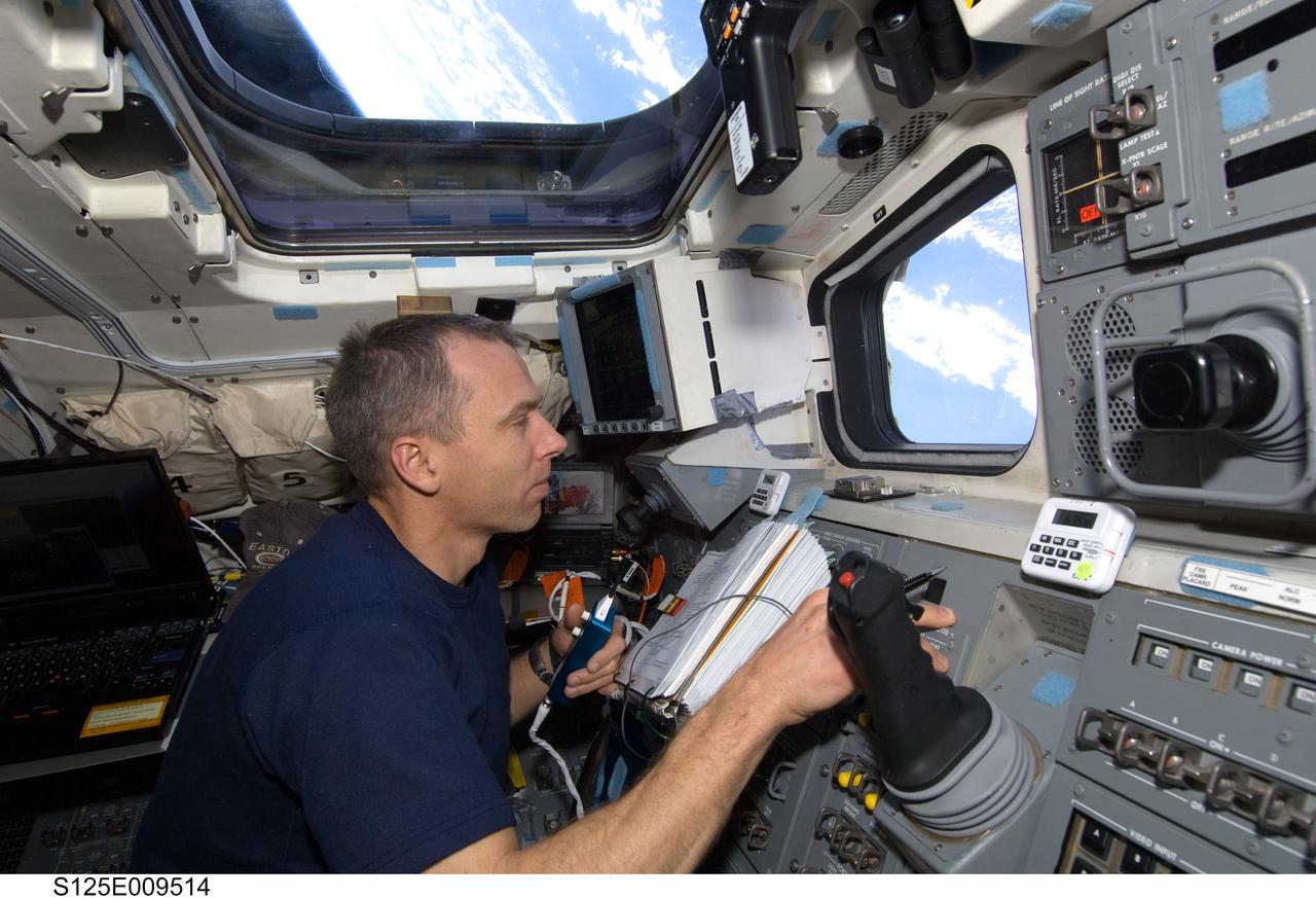 S125-E-009514 (17 May 2009) --- Astronaut Andrew Feustel, STS-125 mission specialist, looks through a window on the aft flight deck of the Earth-orbiting Space Shuttle Atlantis during flight day seven activities.