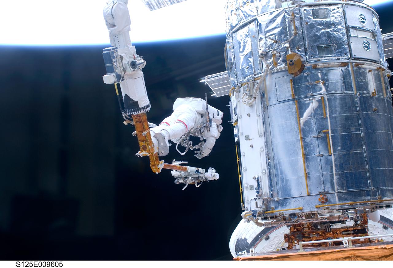 S125-E-009605 (18 May 2009) --- Astronaut John Grunsfeld, STS-125 mission specialist, positioned on a foot restraint on the end of Atlantis? remote manipulator system (RMS), participates in the mission?s fifth and final session of extravehicular activity (EVA) as work continues to refurbish and upgrade the Hubble Space Telescope. During the seven-hour and two-minute spacewalk, Grunsfeld and astronaut Andrew Feustel (out of frame), mission specialist, installed a battery group replacement, removed and replaced a Fine Guidance Sensor and three thermal blankets (NOBL) protecting Hubble?s electronics.