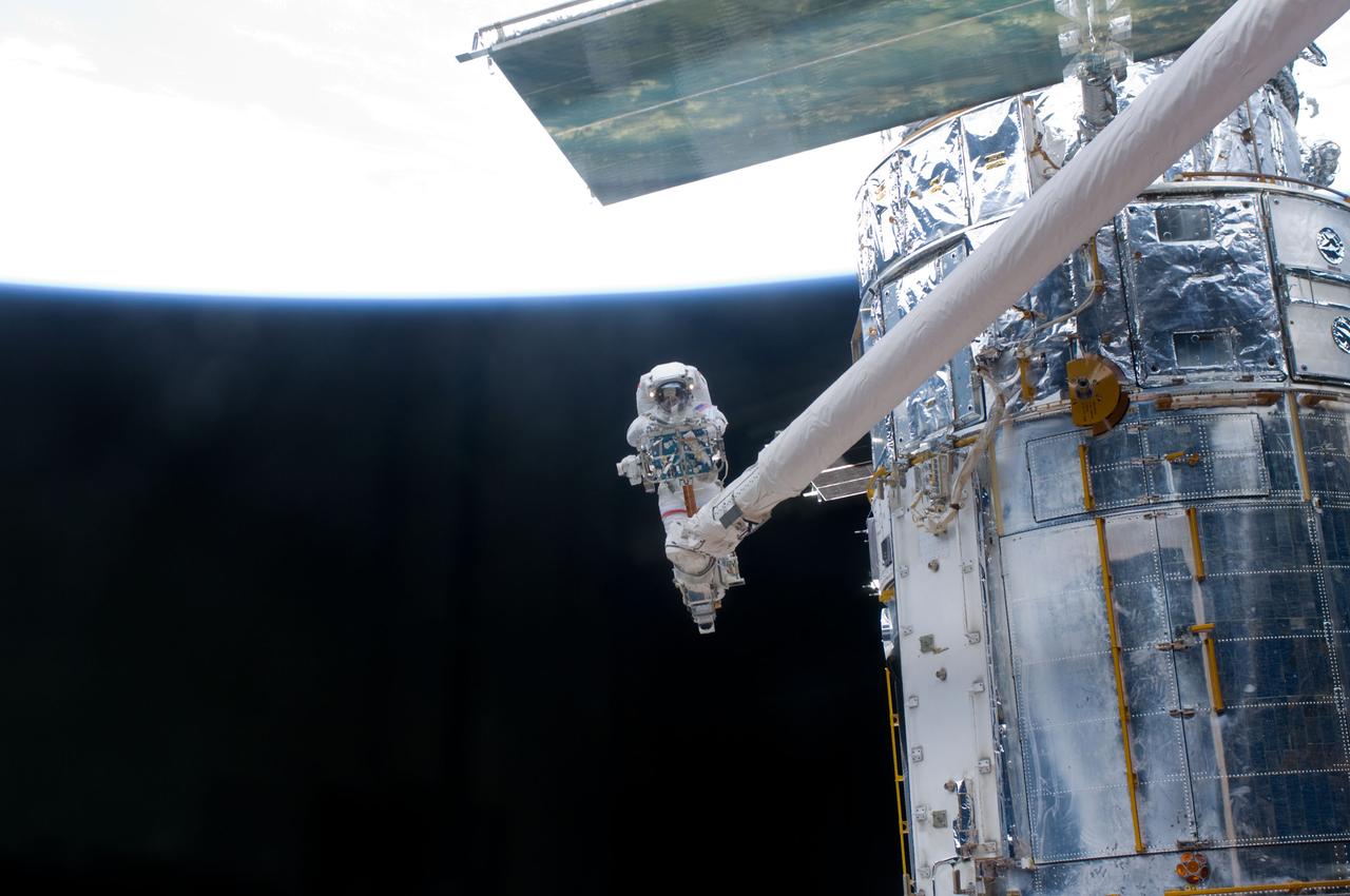 S125-E-009606 (18 May 2009) --- Astronaut John Grunsfeld, STS-125 mission specialist, positioned on a foot restraint on the end of Atlantis? remote manipulator system (RMS), participates in the mission?s fifth and final session of extravehicular activity (EVA) as work continues to refurbish and upgrade the Hubble Space Telescope. During the seven-hour and two-minute spacewalk, Grunsfeld and astronaut Andrew Feustel (out of frame), mission specialist, installed a battery group replacement, removed and replaced a Fine Guidance Sensor and three thermal blankets (NOBL) protecting Hubble?s electronics.