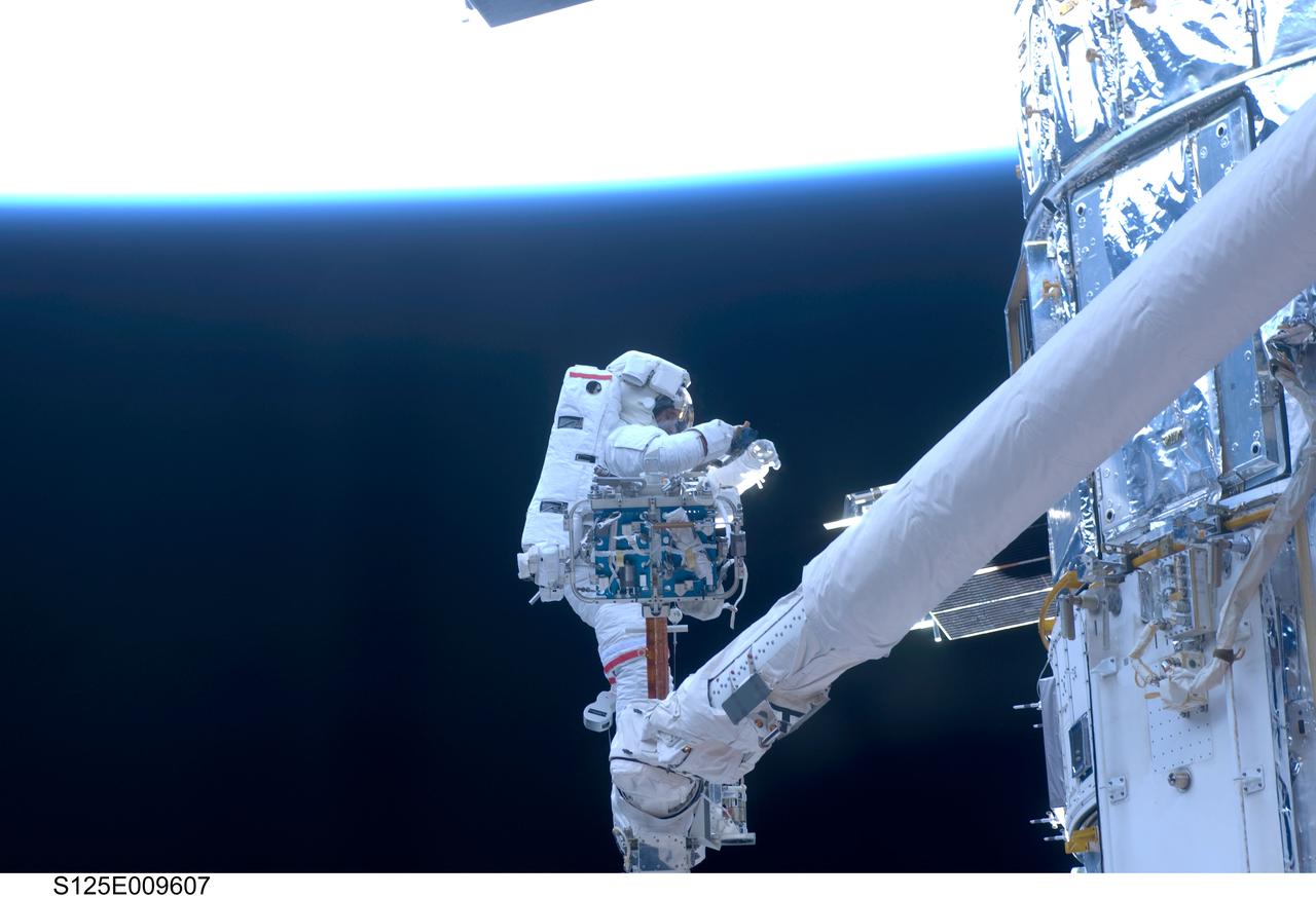 S125-E-009607 (18 May 2009) --- Astronaut John Grunsfeld, STS-125 mission specialist, positioned on a foot restraint on the end of Atlantis? remote manipulator system (RMS), participates in the mission?s fifth and final session of extravehicular activity (EVA) as work continues to refurbish and upgrade the Hubble Space Telescope. During the seven-hour and two-minute spacewalk, Grunsfeld and astronaut Andrew Feustel (out of frame), mission specialist, installed a battery group replacement, removed and replaced a Fine Guidance Sensor and three thermal blankets (NOBL) protecting Hubble?s electronics.