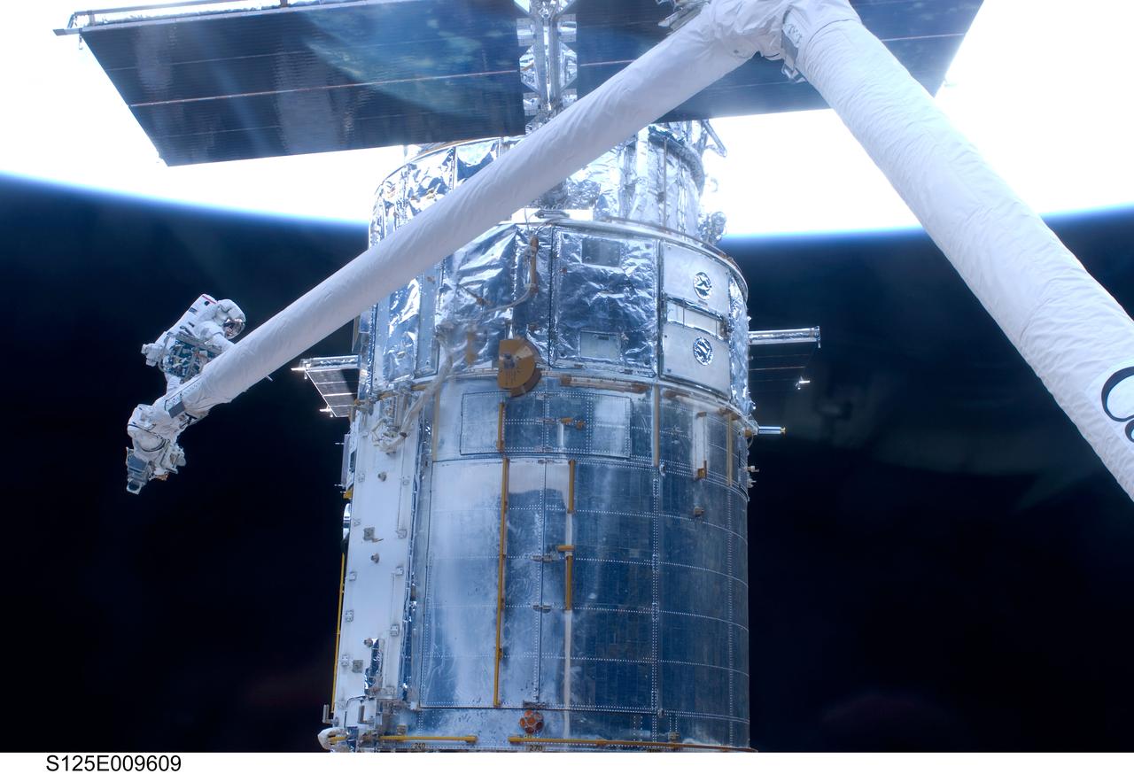 S125-E-009609 (18 May 2009) --- Astronaut John Grunsfeld, STS-125 mission specialist, positioned on a foot restraint on the end of Atlantis? remote manipulator system (RMS), participates in the mission?s fifth and final session of extravehicular activity (EVA) as work continues to refurbish and upgrade the Hubble Space Telescope. During the seven-hour and two-minute spacewalk, Grunsfeld and astronaut Andrew Feustel (out of frame), mission specialist, installed a battery group replacement, removed and replaced a Fine Guidance Sensor and three thermal blankets (NOBL) protecting Hubble?s electronics.