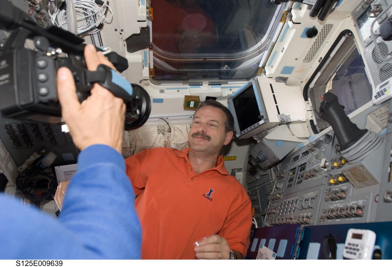 S125-E-009639 (18 May 2009) --- Astronaut Scott Altman, STS-125 commander, is photographed by astronaut Mike Massimino (mostly out of frame at left), mission specialist, on the aft flight deck of the Earth-orbiting Space Shuttle Atlantis during flight day eight activities.