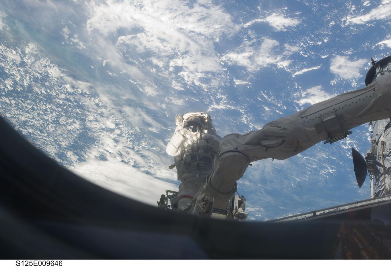 S125-E-009646 (18 May 2009) --- Astronaut John Grunsfeld, STS-125 mission specialist, positioned on a foot restraint on the end of Atlantis? remote manipulator system (RMS), participates in the mission?s fifth and final session of extravehicular activity (EVA) as work continues to refurbish and upgrade the Hubble Space Telescope. During the seven-hour and two-minute spacewalk, Grunsfeld and astronaut Andrew Feustel (out of frame), mission specialist, installed a battery group replacement, removed and replaced a Fine Guidance Sensor and three thermal blankets (NOBL) protecting Hubble?s electronics.