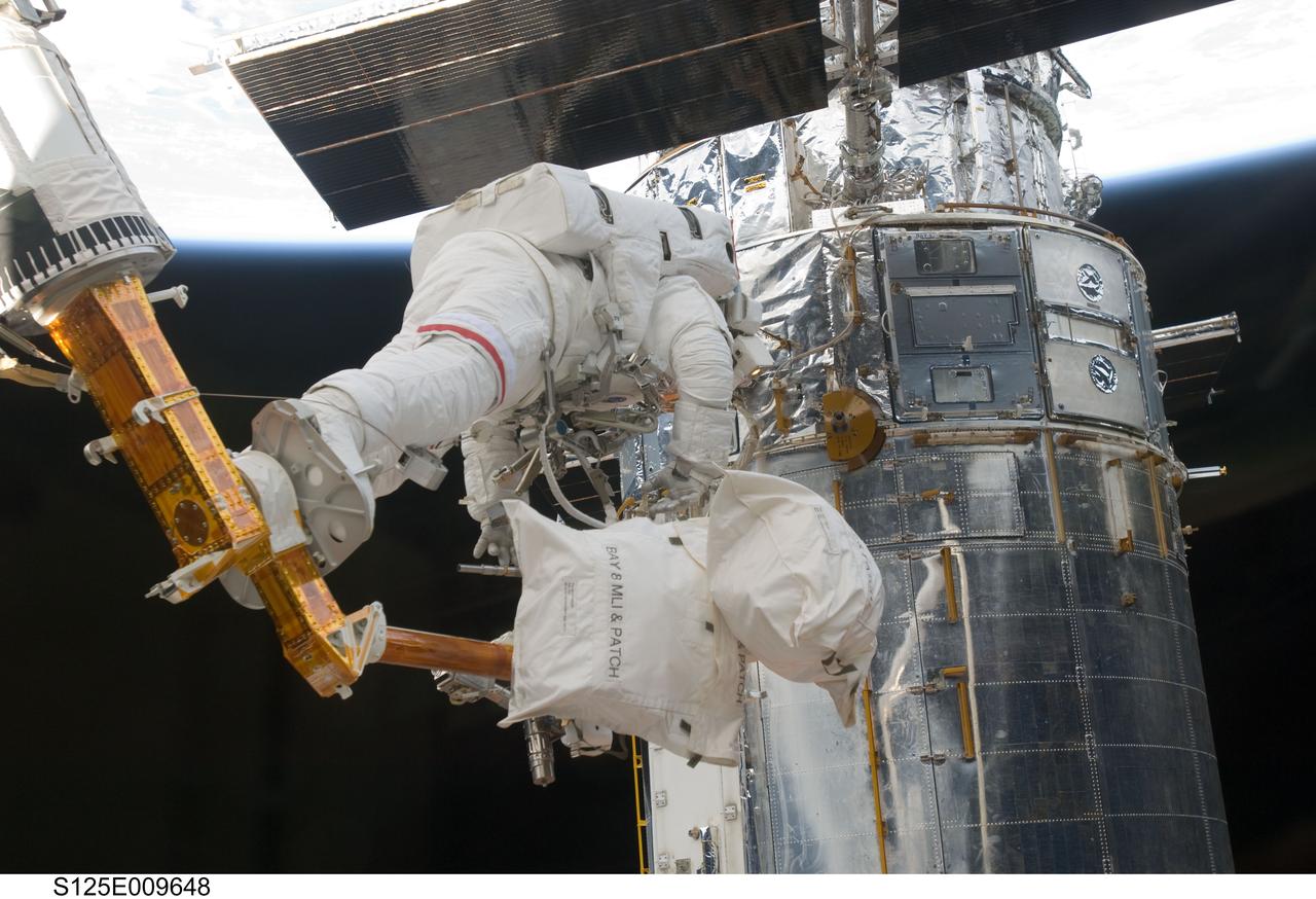 S125-E-009648 (18 May 2009) --- Astronaut John Grunsfeld, STS-125 mission specialist, positioned on a foot restraint on the end of Atlantis? remote manipulator system (RMS), participates in the mission?s fifth and final session of extravehicular activity (EVA) as work continues to refurbish and upgrade the Hubble Space Telescope. During the seven-hour and two-minute spacewalk, Grunsfeld and astronaut Andrew Feustel (out of frame), mission specialist, installed a battery group replacement, removed and replaced a Fine Guidance Sensor and three thermal blankets (NOBL) protecting Hubble?s electronics.