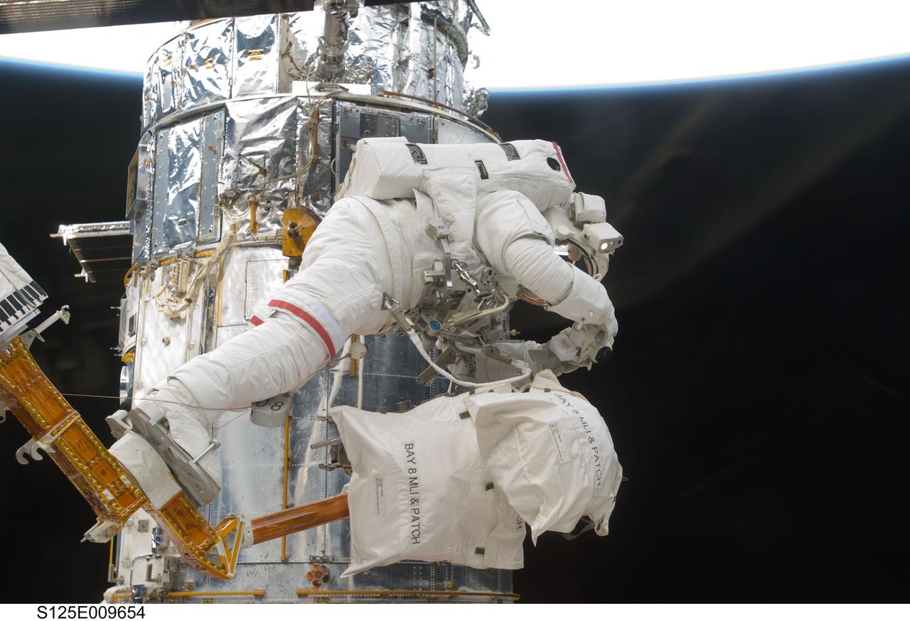 S125-E-009654 (18 May 2009) --- Astronaut John Grunsfeld, STS-125 mission specialist, positioned on a foot restraint on the end of Atlantis? remote manipulator system (RMS), participates in the mission?s fifth and final session of extravehicular activity (EVA) as work continues to refurbish and upgrade the Hubble Space Telescope. During the seven-hour and two-minute spacewalk, Grunsfeld and astronaut Andrew Feustel (out of frame), mission specialist, installed a battery group replacement, removed and replaced a Fine Guidance Sensor and three thermal blankets (NOBL) protecting Hubble?s electronics.