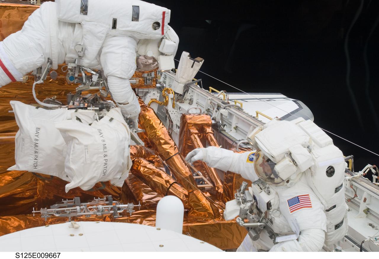 S125-E-009667 (18 May 2009) --- Astronauts John Grunsfeld (left) and Andrew Feustel, both STS-125 mission specialists, participate in the mission?s fifth and final session of extravehicular activity (EVA) as work continues to refurbish and upgrade the Hubble Space Telescope. During the seven-hour and two-minute spacewalk, Grunsfeld and Feustel installed a battery group replacement, removed and replaced a Fine Guidance Sensor and three thermal blankets (NOBL) protecting Hubble?s electronics.