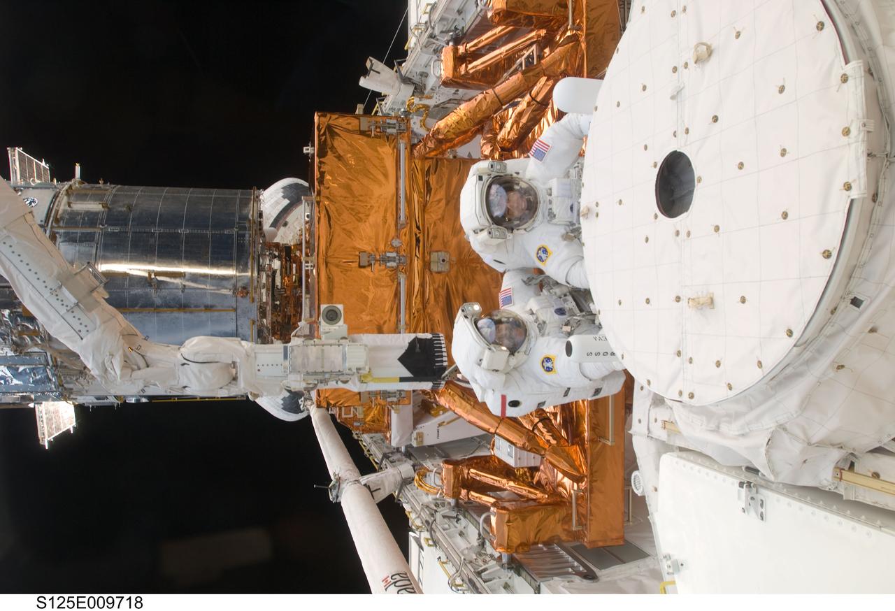 S125-E-009718 (18 May 2009) --- Astronauts John Grunsfeld (bottom) and Andrew Feustel, both STS-125 mission specialists, participate in the mission?s fifth and final session of extravehicular activity (EVA) as work continues to refurbish and upgrade the Hubble Space Telescope. During the seven-hour and two-minute spacewalk, Grunsfeld and Feustel installed a battery group replacement, removed and replaced a Fine Guidance Sensor and three thermal blankets (NOBL) protecting Hubble?s electronics.