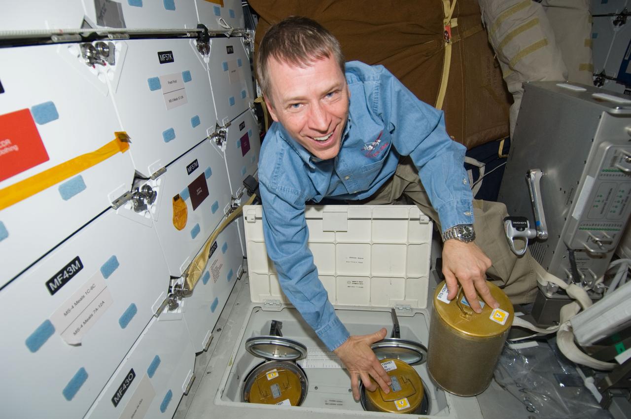 S125-E-009752 (18 May 2009) --- Astronaut Gregory C. Johnson, STS-125 pilot, works with lithium hydroxide (LiOH) canisters from beneath Space Shuttle Atlantis' middeck during flight day eight activities.
