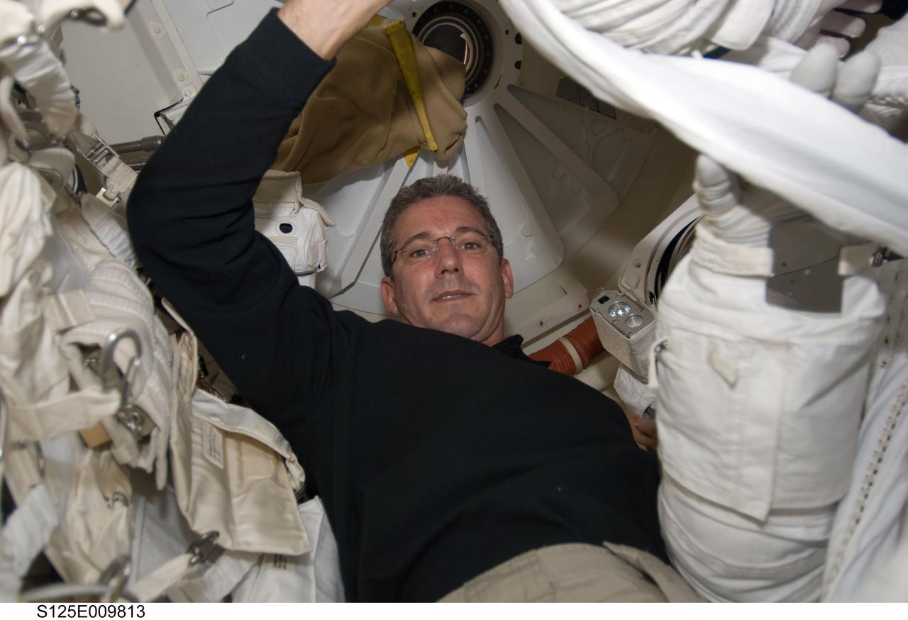 S125-E-009813 (18 May 2009) --- Astronaut Michael Good, STS-125 mission specialist, is surrounded by spacesuit gear in the Earth-orbiting Space Shuttle Atlantis? airlock during flight day eight activities.