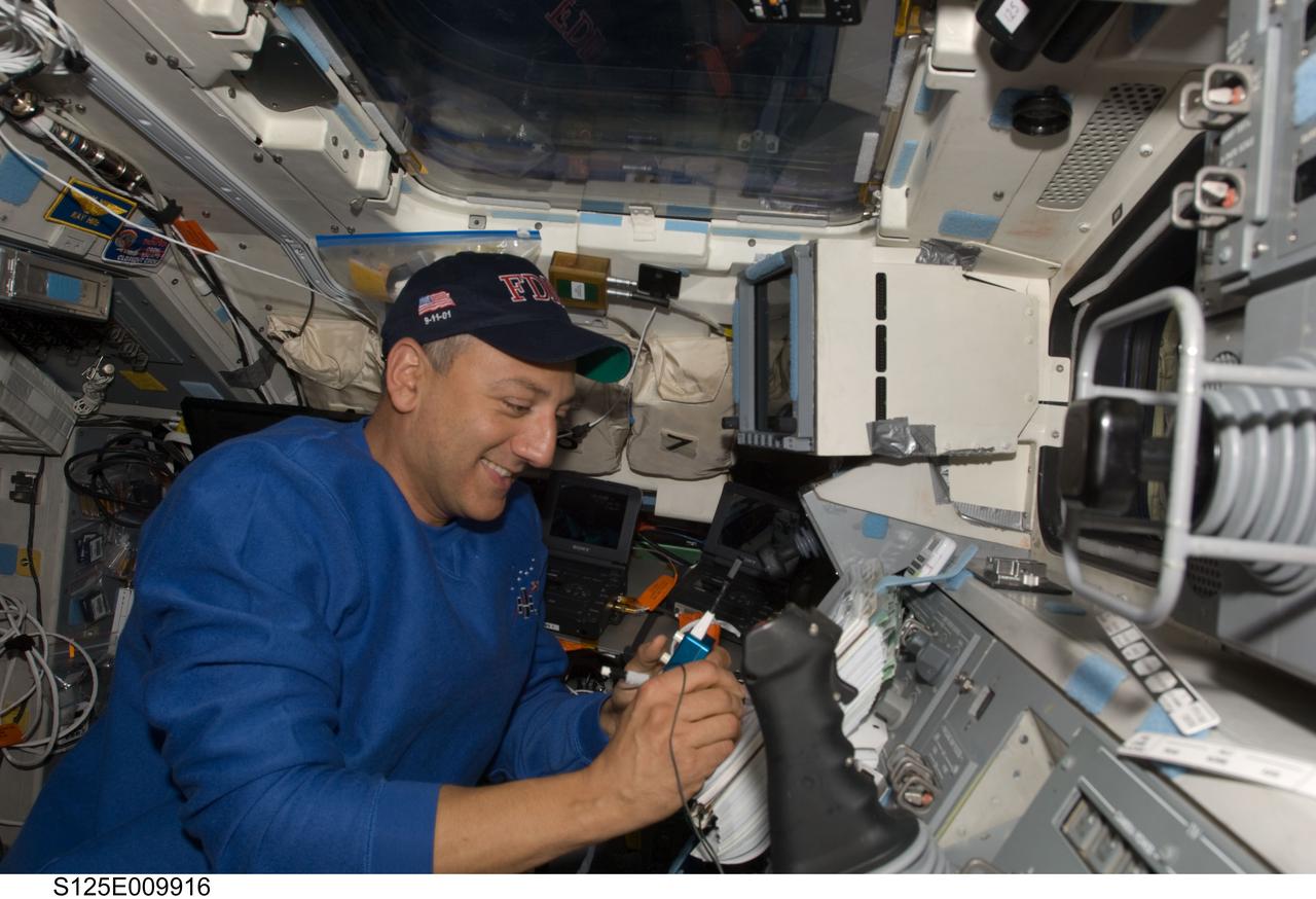 S125-E-009916 (18 May 2009) --- Astronaut Mike Massimino, STS-125 mission specialist, writes notes on a checklist on the aft flight deck of the Earth-orbiting Space Shuttle Atlantis during flight day eight activities.