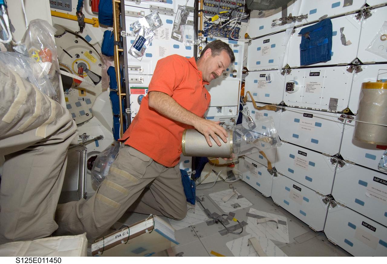 S125-E-011450 (18 May 2009) --- Astronaut Scott Altman, STS-125 commander, works with lithium hydroxide (LiOH) canisters from beneath Space Shuttle Atlantis' middeck during flight day eight activities.