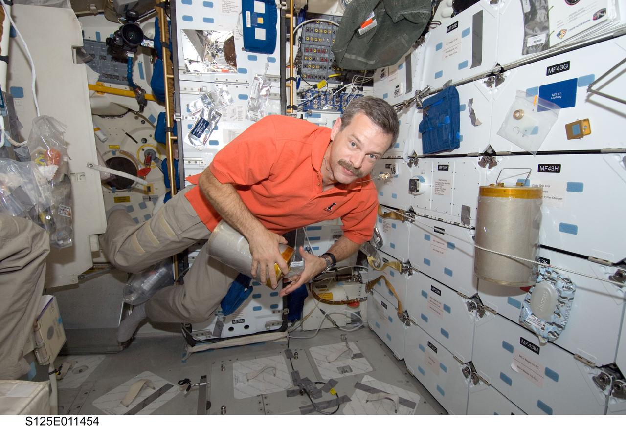 S125-E-011454 (18 May 2009) --- Astronaut Scott Altman, STS-125 commander, works with lithium hydroxide (LiOH) canisters from beneath Space Shuttle Atlantis' middeck during flight day eight activities.