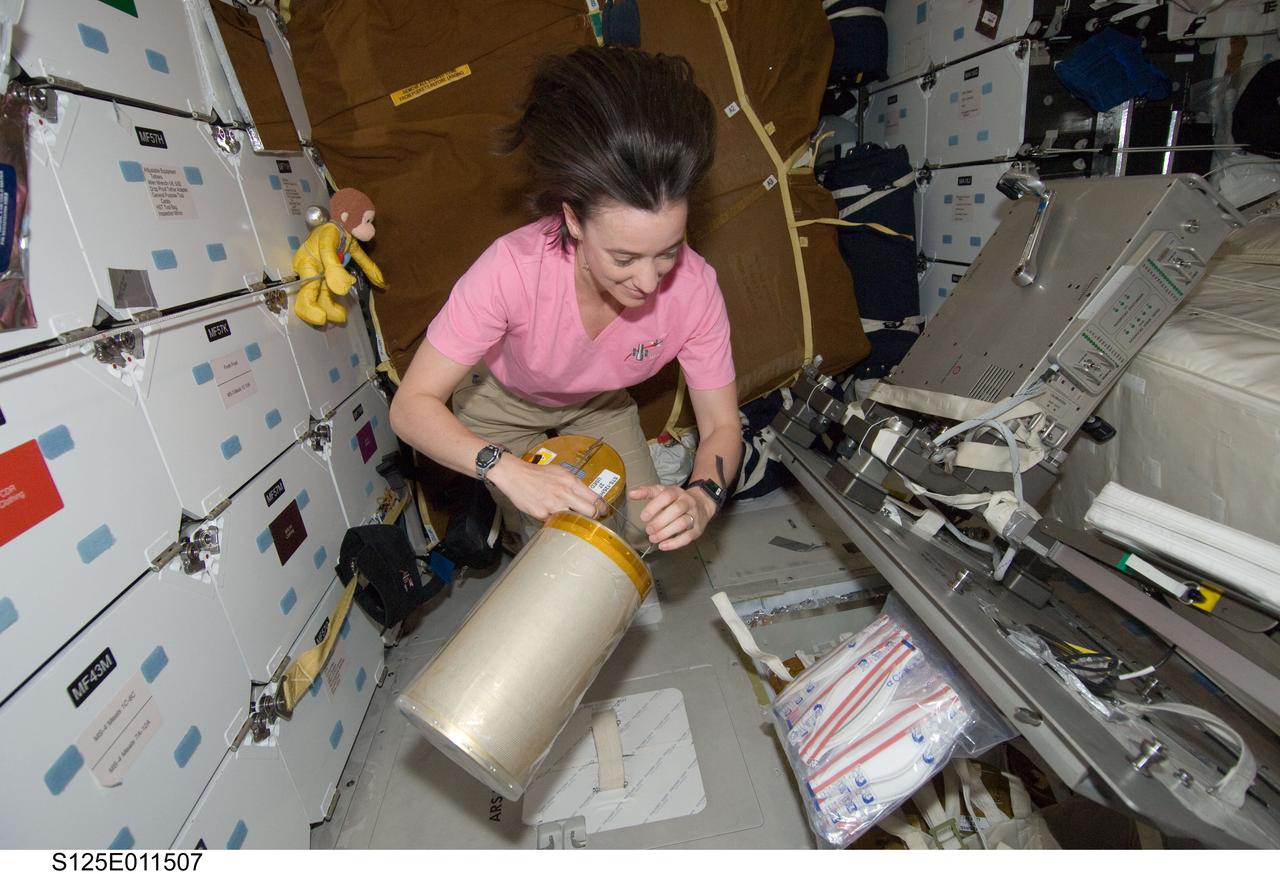 S125-E-011507 (19 May 2009) --- Astronaut Megan McArthur, STS-125 mission specialist, works with lithium hydroxide (LiOH) canisters from beneath Space Shuttle Atlantis' middeck during flight day nine activities.