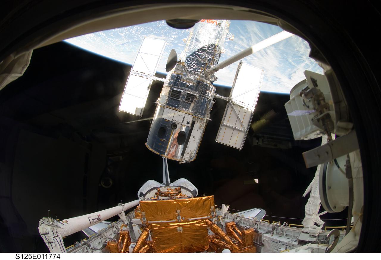 S125-E-011774 (19 May 2009) --- The Space Shuttle Atlantis? remote manipulator system arm lifts the Hubble Space Telescope from the cargo bay and is moments away from releasing the orbital observatory to start it on its way back home to observe the universe.