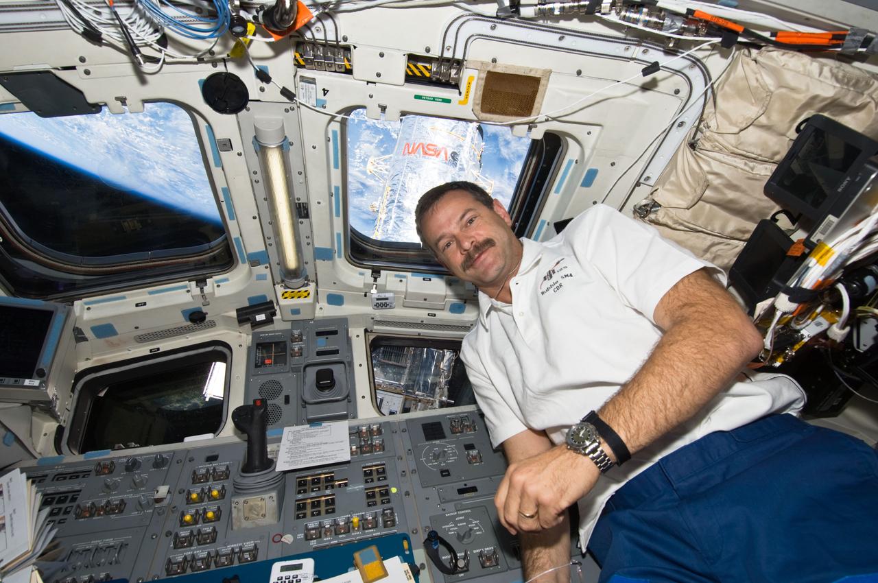 S125-E-011893 (19 May 2009) --- Astronaut Scott Altman, STS-125 commander, is pictured on the aft flight deck of the Earth-orbiting Space Shuttle Atlantis during flight day nine activities. A portion of the Hubble Space Telescope and Earth?s horizon are visible through the overhead windows.