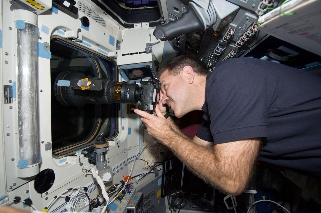 S125-E-011919 (19 May 2009) --- Astronaut John Grunsfeld, STS-125 mission specialist, uses a still camera at an overhead window on the aft flight deck of the Earth-orbiting Space Shuttle Atlantis to photograph the Hubble Space Telescope after its release from Atlantis? remote manipulator system (RMS) robotic arm.