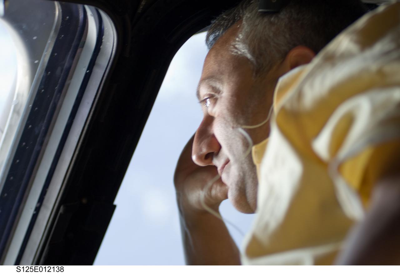S125-E-012138 (19 May 2009) --- Astronaut Mike Massimino, STS-125 mission specialist, looks through a window on the aft flight deck of the Earth-orbiting Space Shuttle Atlantis.