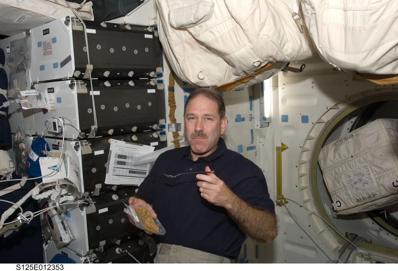 S125-E-012353 (19 May 2009) --- Astronaut John Grunsfeld, STS-125 mission specialist, eats a meal on the middeck of the Earth-orbiting Space Shuttle Atlantis.