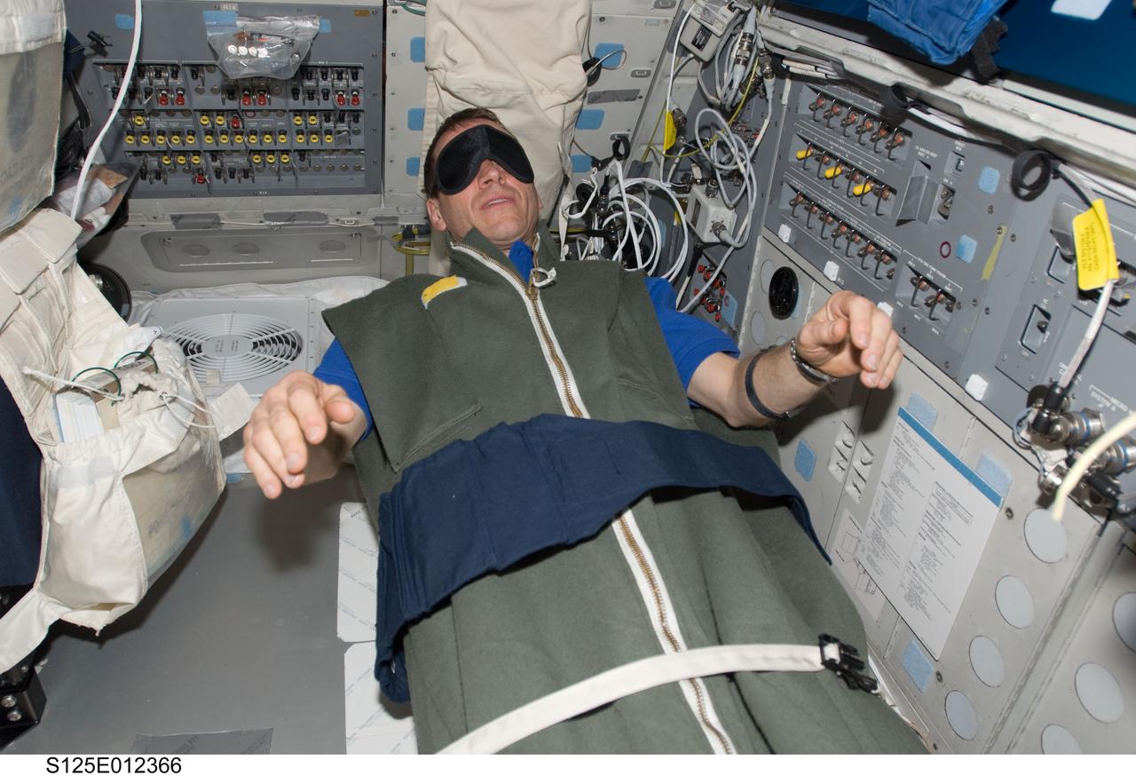 S125-E-012366 (20 May 2009) --- Astronaut Gregory C. Johnson, STS-125 pilot, rests in his sleeping bag on the flight deck of the Earth-orbiting Space Shuttle Atlantis at the end of flight day 10.