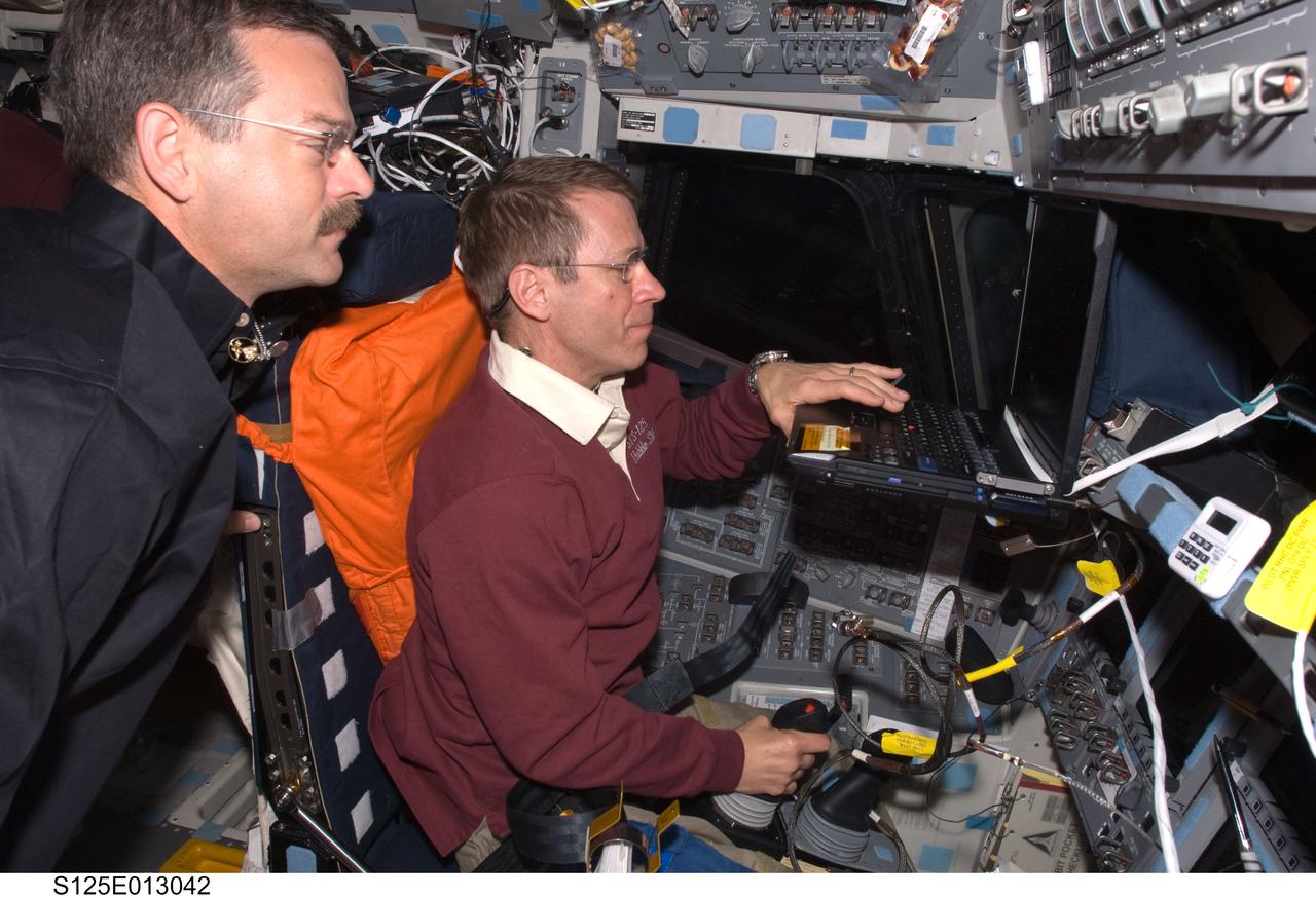 S125-E-013042 (21 May 2009) --- Occupying the commander?s station, astronaut Gregory C. Johnson, STS-125 pilot, uses the Portable In-Flight Landing Operations Trainer (PILOT) on the flight deck of the Earth-orbiting Space Shuttle Atlantis. PILOT consists of a laptop computer and a joystick system, which helps to maintain a high level of proficiency for the end-of-mission approach and landing tasks required to bring the shuttle safely back to Earth. Astronaut Scott Altman, commander, looks on.