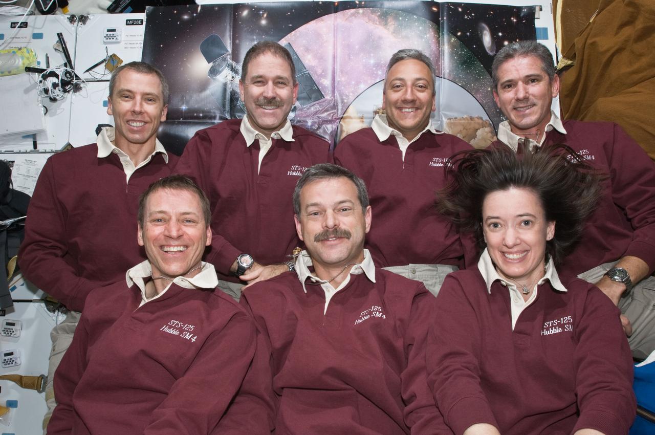 S125-E-013380 (21 May 2009) --- The crewmembers for the STS-125 mission pose for a photo on the middeck of the Earth-orbiting Space Shuttle Atlantis. Pictured on the front row are astronauts Scott Altman (center), commander; Gregory C. Johnson, pilot; and Megan McArthur, mission specialist. Pictured on the back row (left to right) are astronauts Andrew Feustel, John Grunsfeld, Mike Massimino and Michael Good, all mission specialists.