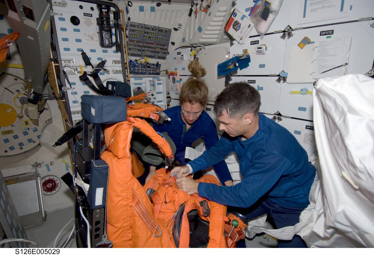 S126-E-005029 (14 Nov. 2008) --- Astronauts Shane Kimbrough and Sandra Magnus, both STS-126 mission specialists, work with their shuttle launch and entry suits on the middeck of Space Shuttle Endeavour during post launch activities.