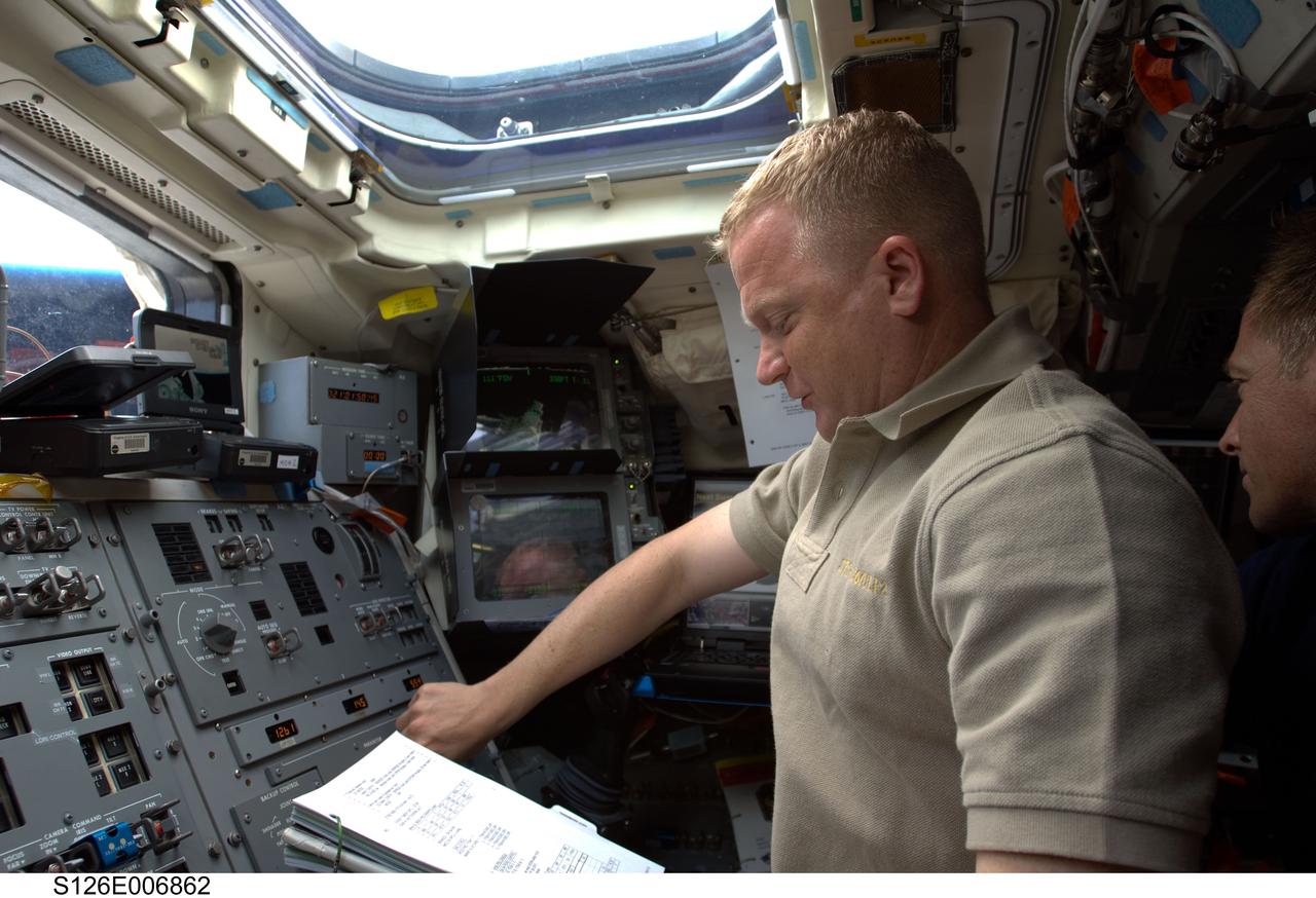 S126-E-006862 (15 Nov. 2008) --- Astronaut Eric Boe, STS-126 pilot, looks over a checklist while working with controls on the aft flight deck of Space Shuttle Endeavour during flight day two activities.