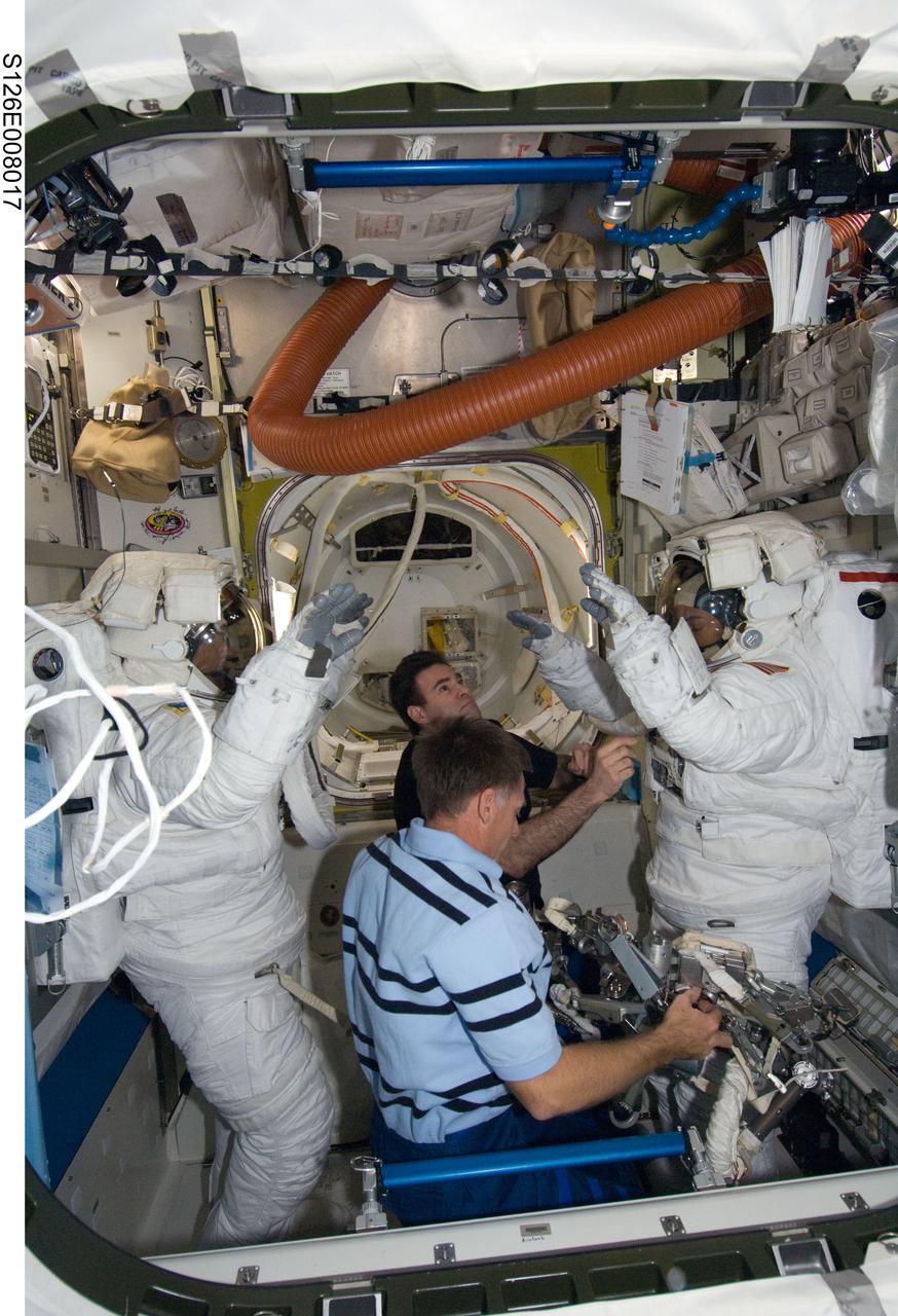 S126-E-008017 (18 Nov. 2008) --- Attired in their Extravehicular Mobility Unit (EMU) spacesuits, astronauts Heidemarie Stefanyshyn-Piper (right) and Steve Bowen, both STS-126 mission specialists, are pictured in the Quest Airlock of the International Space Station as the mission’s first session of extravehicular activity (EVA) draws to a close. Astronauts Chris Ferguson (foreground, center), STS-126 commander, and Greg Chamitoff, mission specialist, assist with the doffing of the spacesuits.