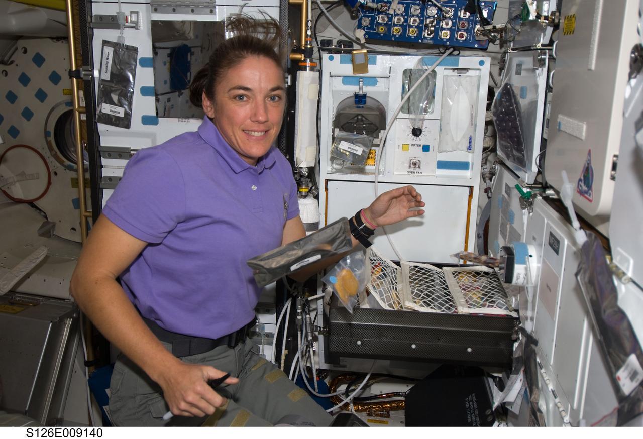 S126-E-009140 (23 Nov. 2008) --- Astronaut Heidemarie Stefanyshyn-Piper, STS-126 mission specialist, takes a moment for a photo as she makes her selection for a meal at the galley on the middeck of Space Shuttle Endeavour while docked with the International Space Station.