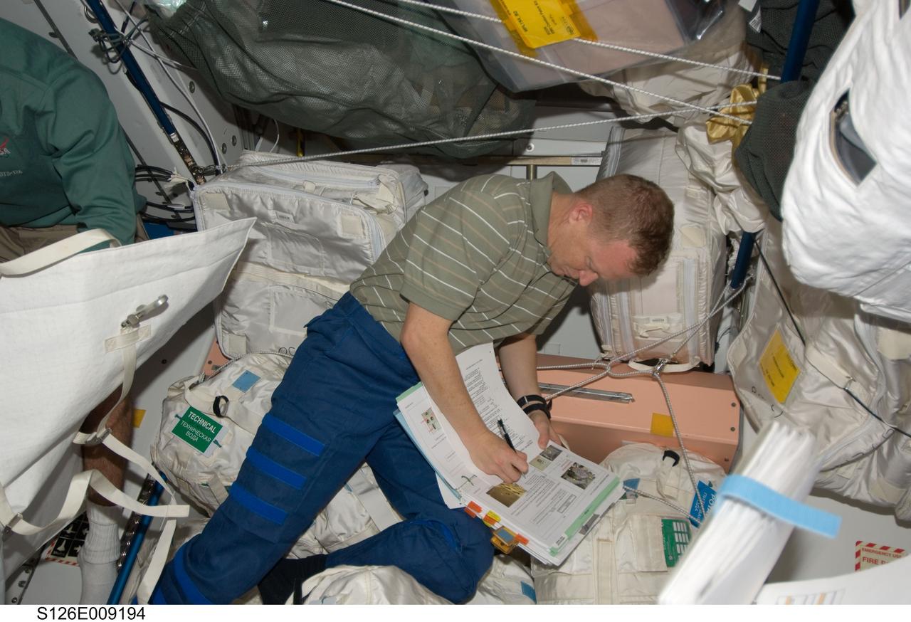 S126-E-009194 (23 Nov. 2008) --- Astronaut Eric Boe, STS-126 pilot, makes notations on a procedures manual in the Unity node of the International Space Station while Space Shuttle Endeavour remains docked with the station.