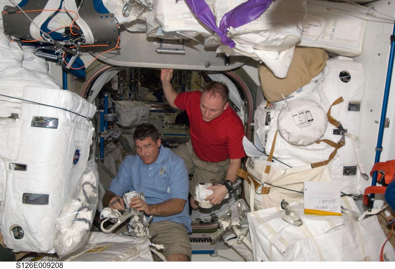S126-E-009208 (23 Nov. 2008) --- Astronauts Steve Bowen (left), STS-126 mission specialist; and Michael Fincke, Expedition 18 commander, work with EVA hardware in the Unity node of the International Space Station while Space Shuttle Endeavour remains docked with the station.