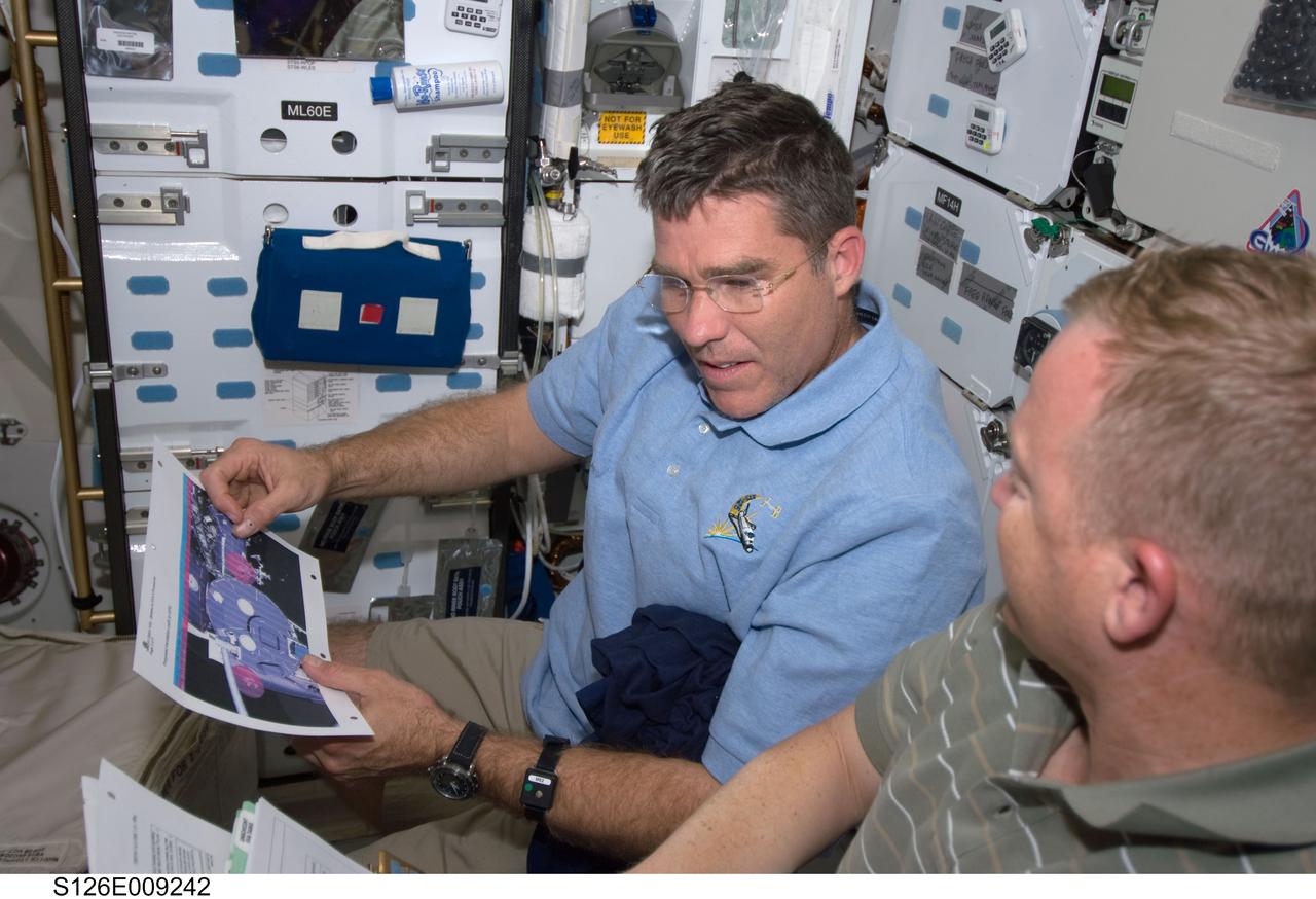 S126-E-009242 (23 Nov. 2008) --- Astronauts Eric Boe (right), STS-126 pilot, and Steve Bowen, mission specialist, look over a procedures manual on the middeck of Space Shuttle Endeavour while docked with the International Space Station.