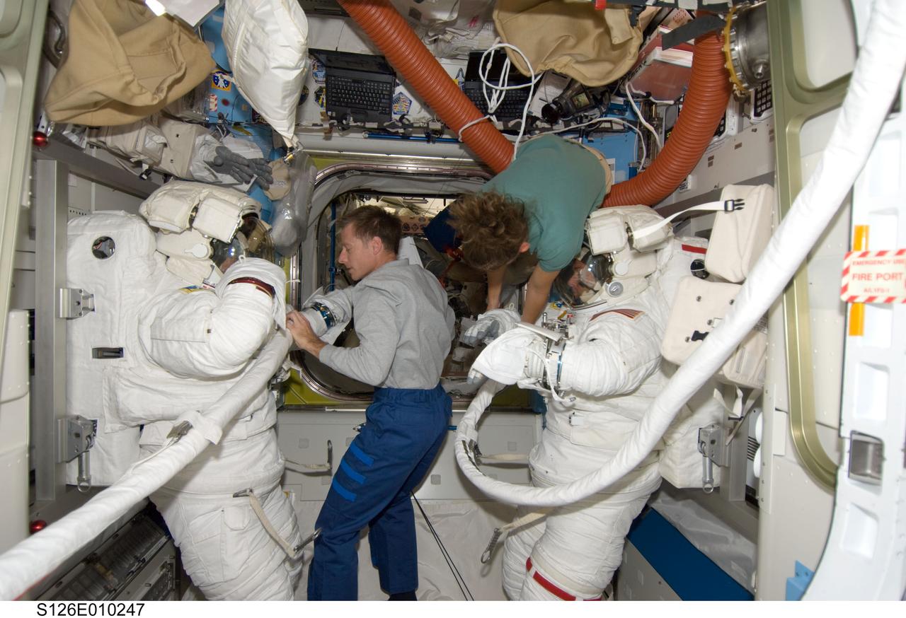 S126-E-010247 (24 Nov. 2008) --- Astronauts Steve Bowen (left) and Shane Kimbrough, both STS-126 mission specialists, attired in their Extravehicular Mobility Unit (EMU) spacesuits, are pictured in the Quest Airlock of the International Space Station as the mission's fourth session of extravehicular activity (EVA) draws to a close. Astronauts Chris Ferguson, commander; and Sandra Magnus, Expedition 18 flight engineer, assist with the doffing of the spacesuits.
